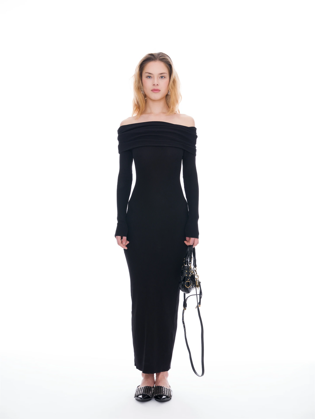 Woman wearing a black off-shoulder dress holding a bag on a white background