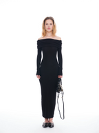 Woman wearing a black off-shoulder dress holding a bag on a white background
