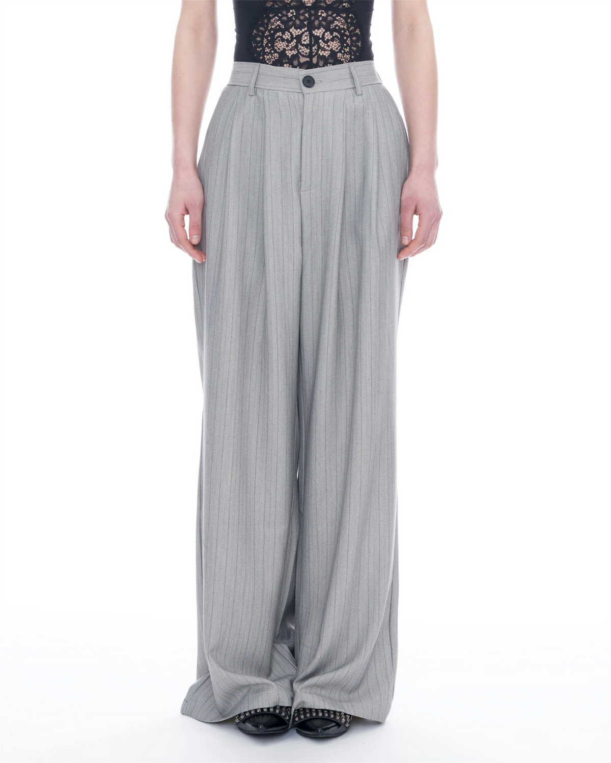 A model is shown from the chest down wearing high-waisted, wide-leg trousers in a light gray and white pinstripe pattern, paired with a black lace top and black shoes.