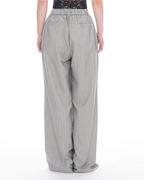 A person shown from the back wearing light gray wide-leg pinstripe trousers with an elastic waistband and back pockets, against a plain white studio background.