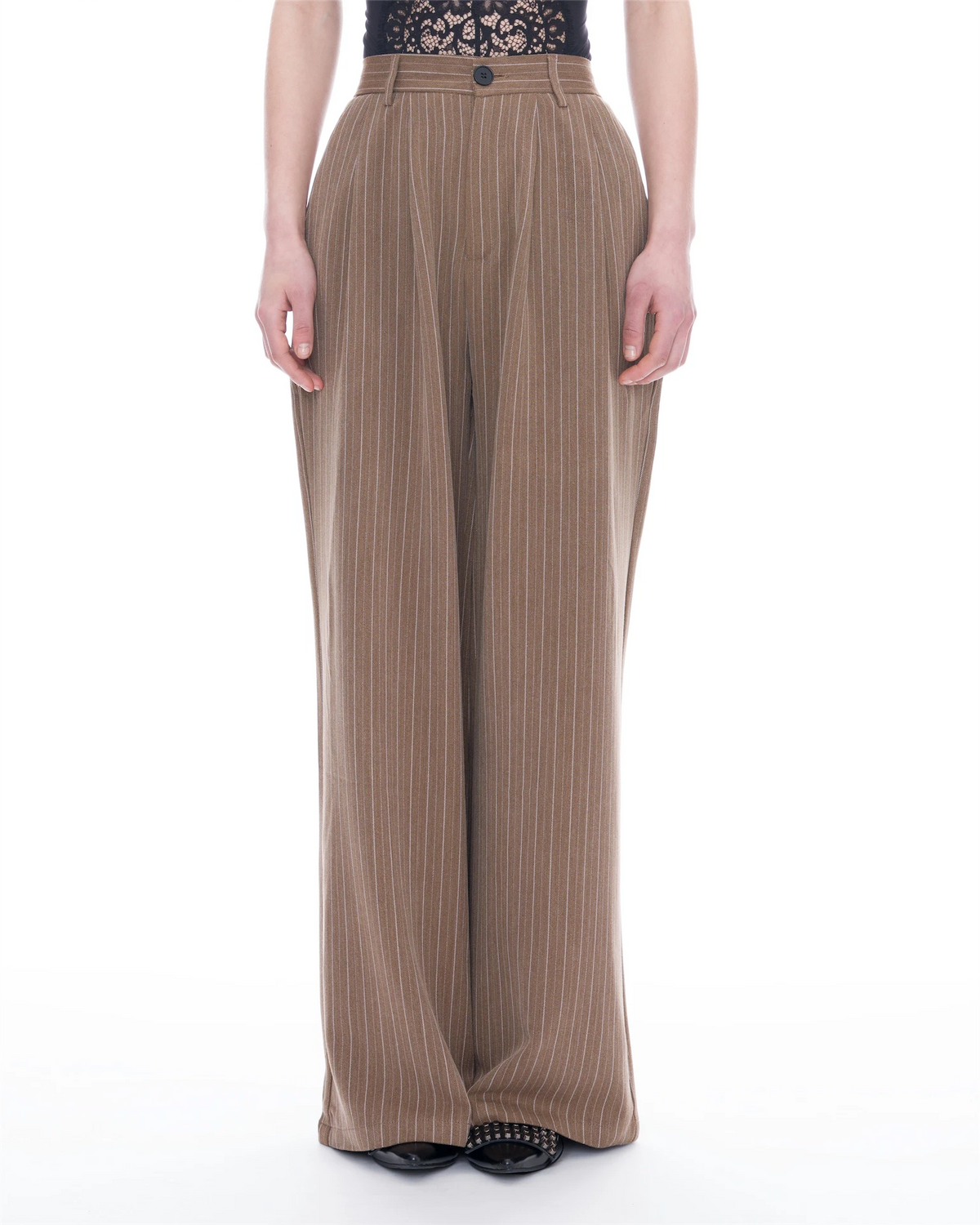 A model is shown from the waist down wearing high-waisted, wide-leg trousers in a brown and beige pinstripe pattern, paired with a black lace-trimmed top and black pointed flat shoes, against a plain white background.