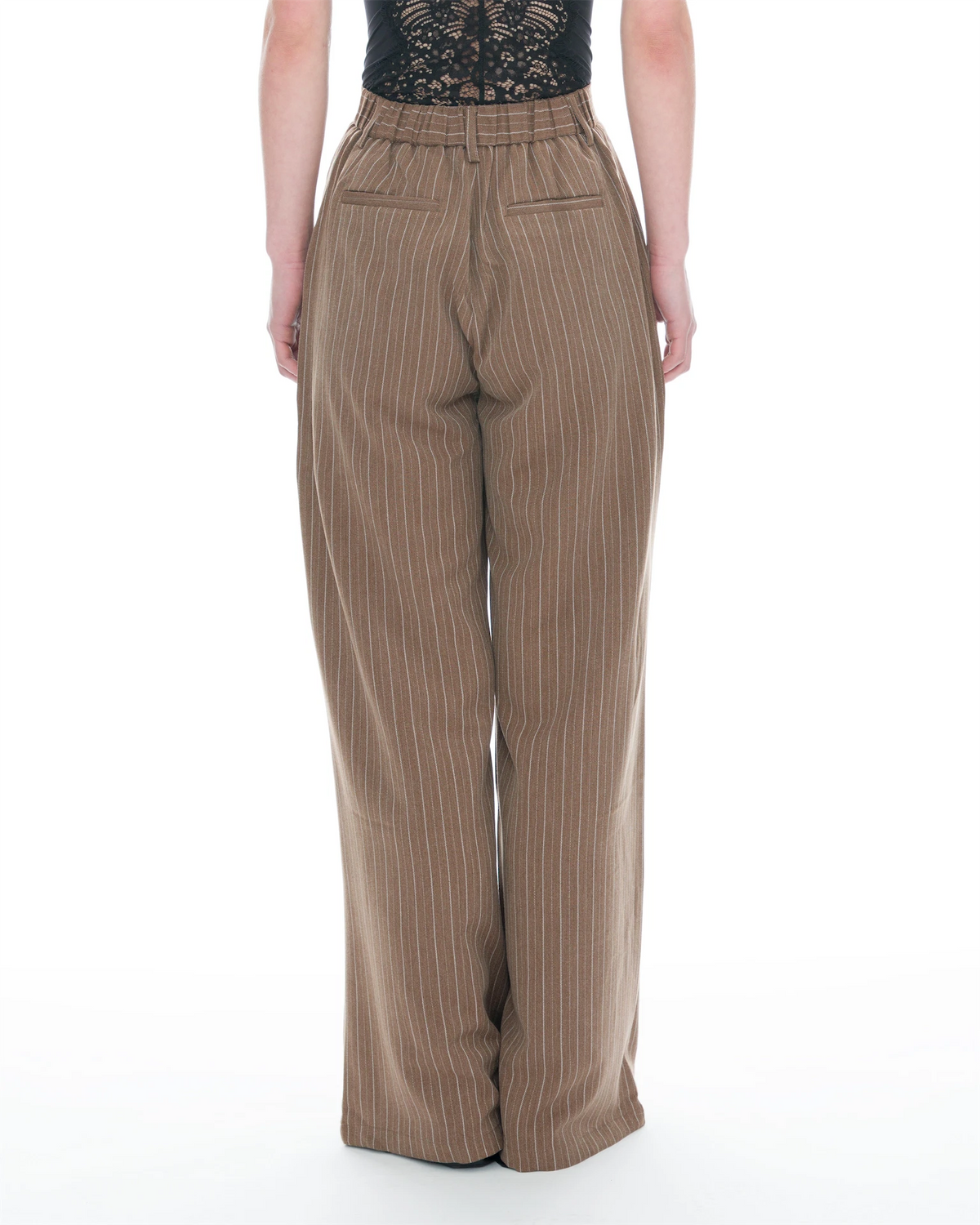A person shown from the back wearing high-waisted, wide-leg trousers in a warm taupe-brown with thin vertical pinstripes, paired with a black lace top, against a plain white studio background.