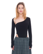 A model wearing a black asymmetrical long-sleeve top with a side cutout and dark green plaid button-front pants, shot against a solid white background.
