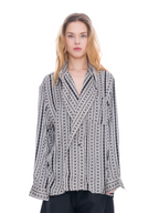 A model wearing a black and white vertically patterned wrap-style shirt jacket with a collar, photographed against a solid white background.