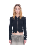 A model wearing a black cropped zip-up jacket with shoulder cutouts and gathered ruffle details at the hem, paired with gray drawstring sweatpants, shot against a solid white background.
