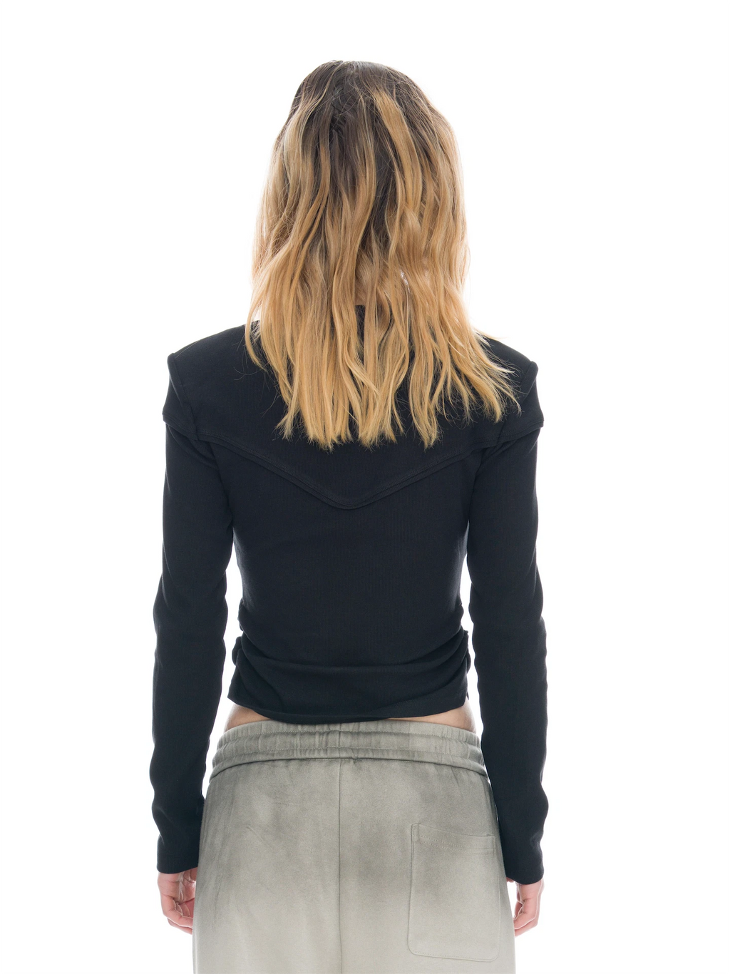 A model shown from the back wearing a black long-sleeve ribbed top with shoulder detailing and light gray sweatpants, set against a solid white background.