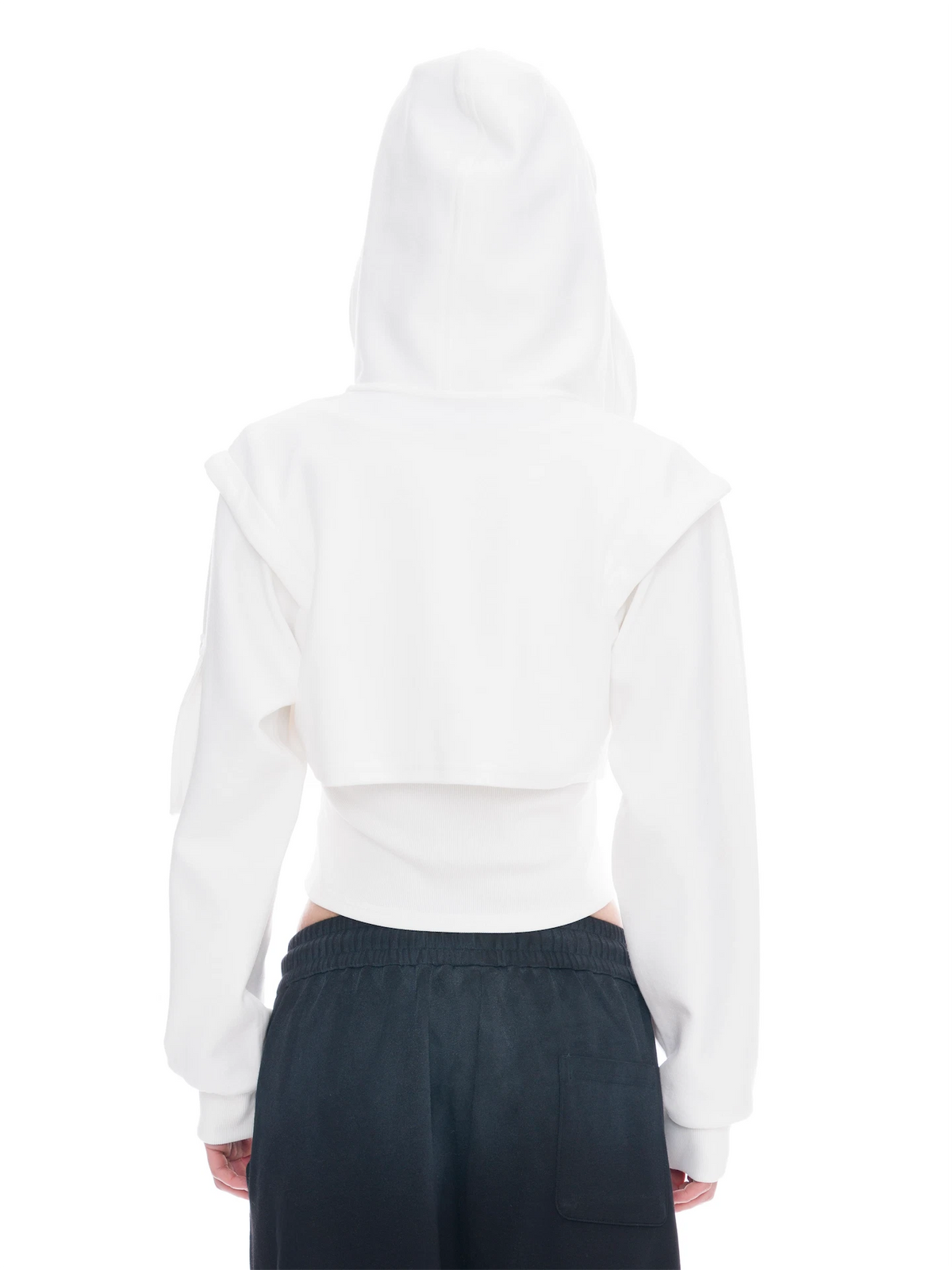 A person shown from the back wearing a white cropped hoodie with wide shoulder panels and dark charcoal pants against a plain white studio background.