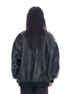 A person viewed from the back wearing an oversized black faux-leather bomber jacket with a gathered elastic hem and cuffs, against a plain white studio background.