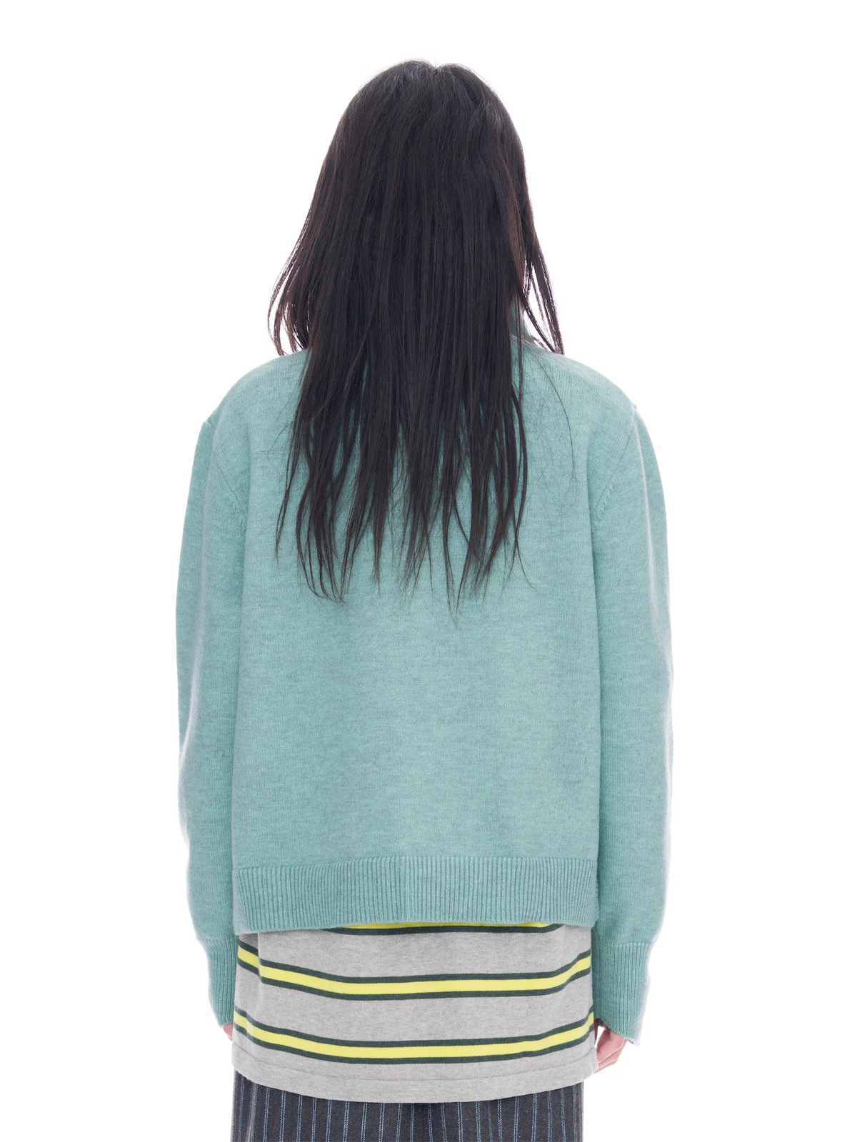 A person viewed from the back wearing a light mint green knit sweater over a gray striped shirt with yellow and green stripes, against a plain white background.