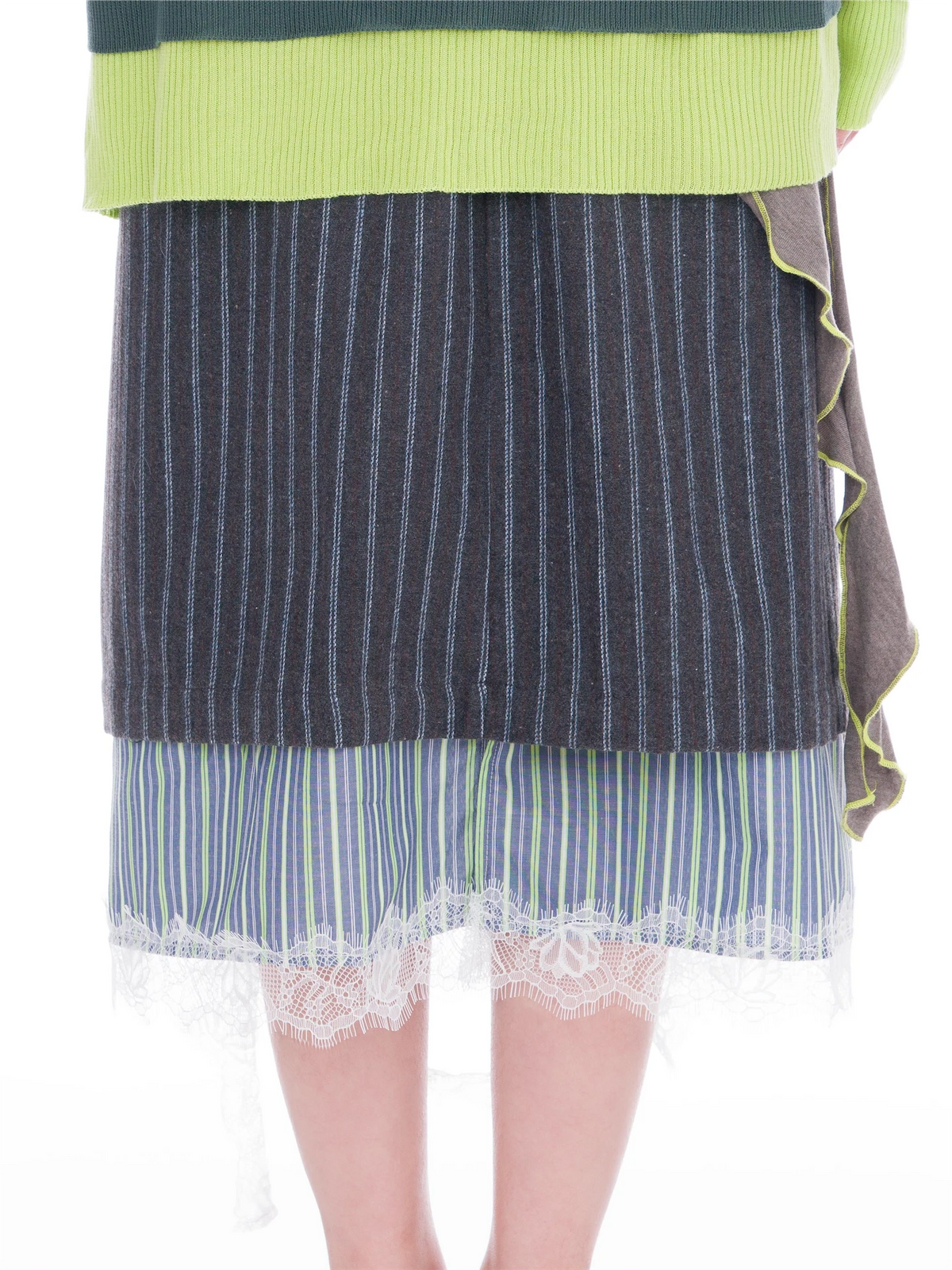 Close-up of a person wearing a layered skirt with a dark navy pinstripe top layer, a green and blue striped mid-layer, and a white lace hem, styled with a lime green top.