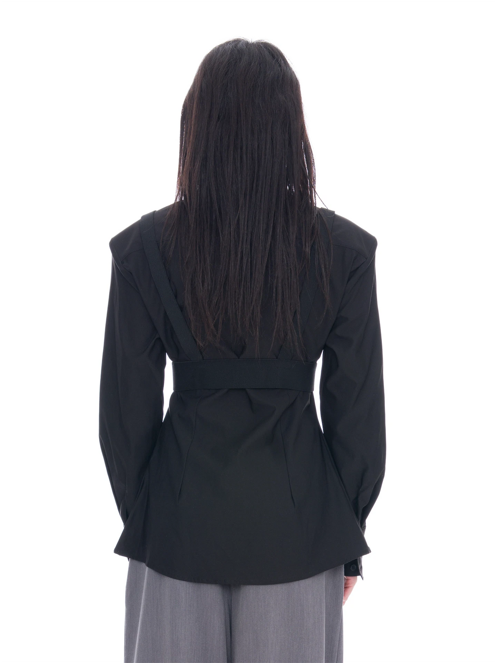 A person viewed from the back wearing a black long-sleeve belted jacket and light gray wide-leg pants against a plain white background.