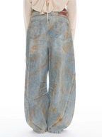 Wide-leg light blue denim jeans with a distressed tan wash pattern, shown from the back on a model wearing a cream top against a white background.