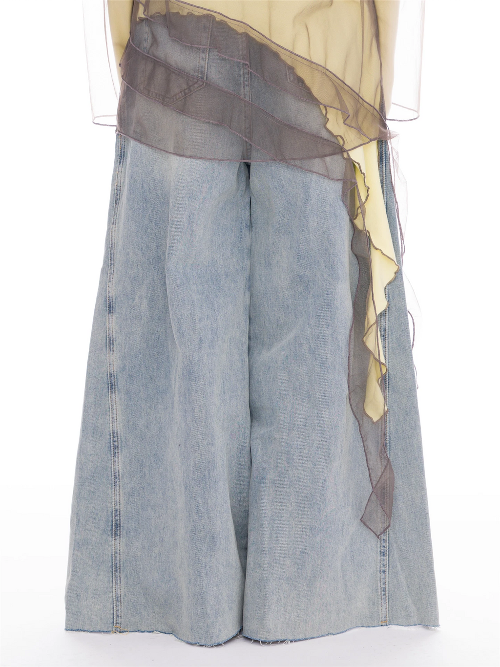 Light-wash wide-leg denim shorts with a sheer dark gray mesh overlay draped over the waist and a yellow underlayer, shown against a plain white background.