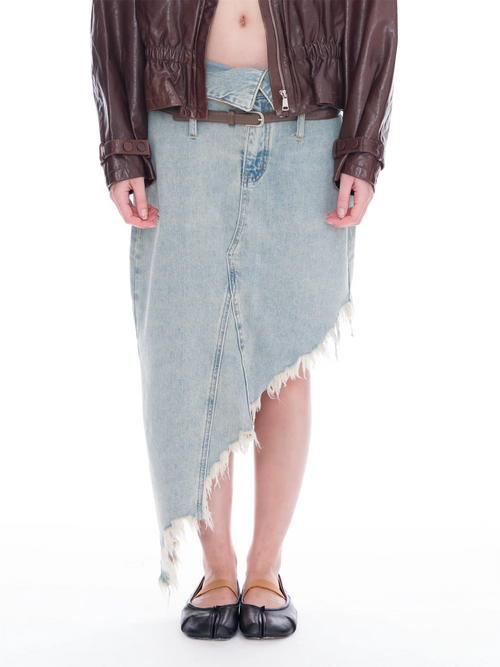 A person wearing a light-wash asymmetrical denim skirt with frayed edges, styled with a brown leather jacket and black flat shoes against a white studio background.